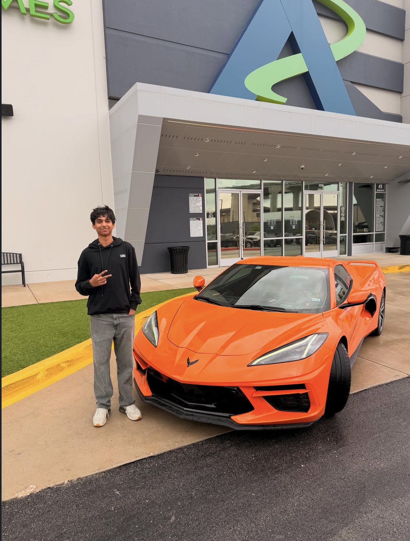 Rehan Raj posing with a Corvette at Andretti's for the Best Day Ever of Edui, ten years in remission from blood cancer, whom Rehan nominated